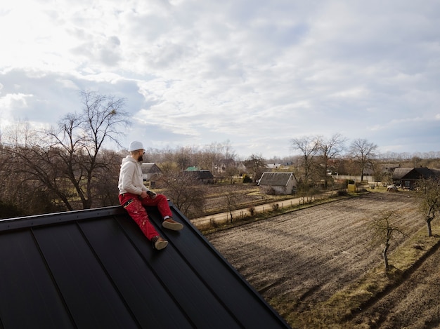 man-with-helmet-sitting-roof-full-shot_23-2149343712