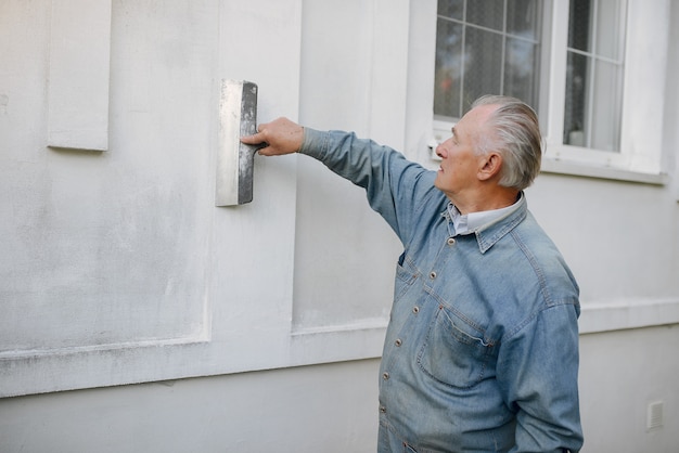 old-man-standing-near-building-with-repair-tools_1157-29768