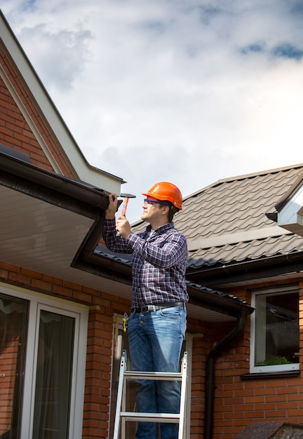 professional-carpenter-standing-high-ladder-repairing-house-roof_454047-6910