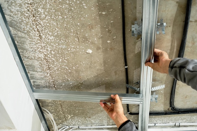 worker-adjusts-metal-profile-mounting-plasterboard-ceiling-frame-close-up-selective-focus-hands-specialist-industrial-renovation-renovation_166373-1907